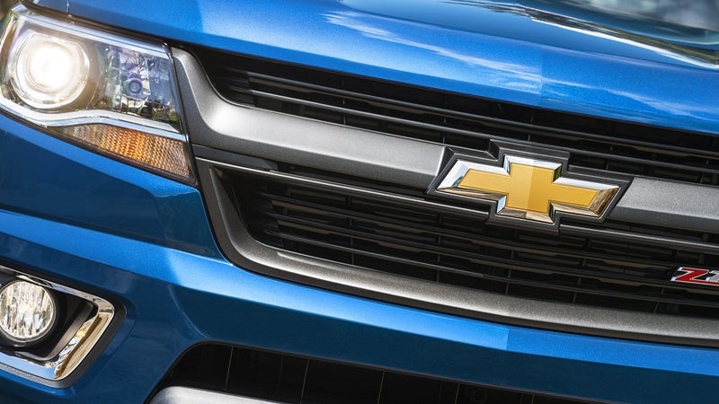 Chevrolet Colorado front grille with gold emblem and headlight.
