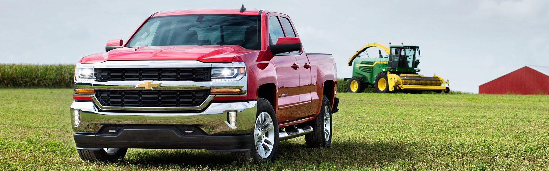 Red Chevrolet Silverado parked on a grassy farm field