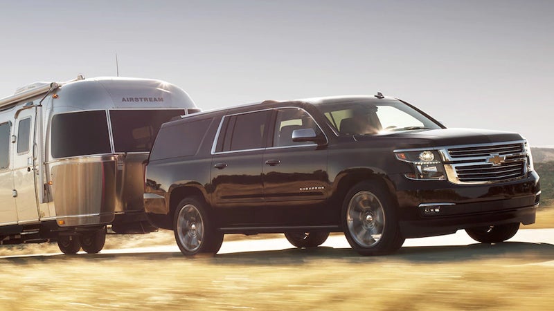 2017 Chevrolet Suburban towing an Airstream trailer at sunset on an open road.