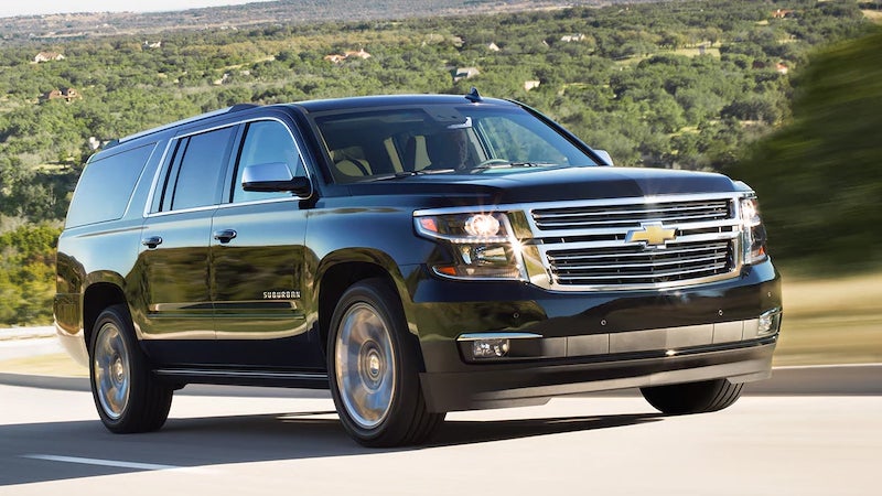 2017 Chevrolet Suburban driving on a highway with scenic hills in the background.
