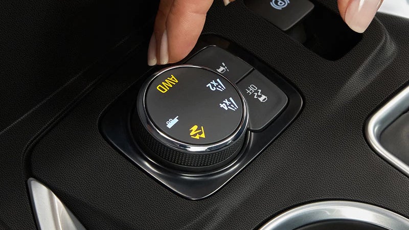 Driver adjusting the traction mode selector knob in the 2018 Chevrolet Traverse.
