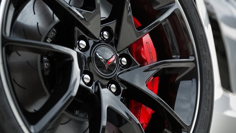 Close-up of a Corvette ZR1 black performance wheel with red brake calipers and slotted brake rotor.