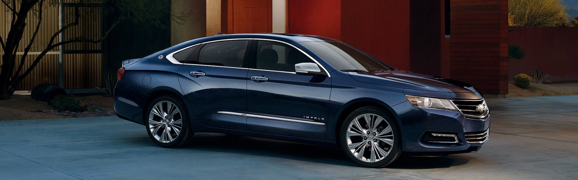 2019 Chevrolet Impala in blue parked in a modern residential driveway, shown from side profile