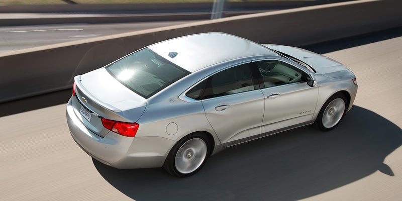 Rear and side view of a silver 2019 Chevrolet Impala driving on the highway, highlighting its aerodynamic shape and LED taillights