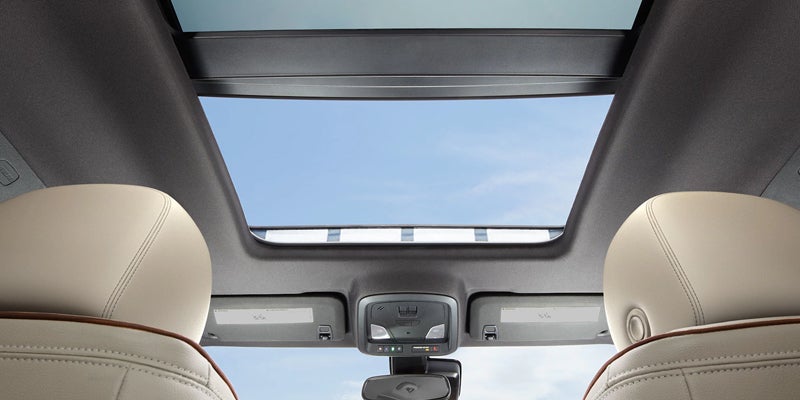 Interior view of the 2019 Chevrolet Impala looking up at the panoramic sunroof from the back seats, blue sky visible
