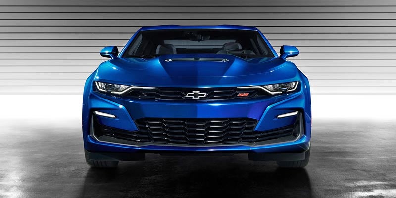 Bold front view of a blue 2021 Chevrolet Camaro showcasing its wide grille, sharp headlights, and hood vent.