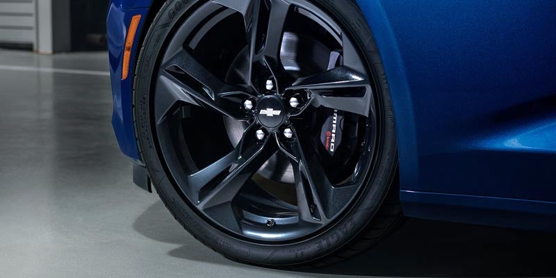 Close-up of the Camaro’s blacked-out alloy wheel with visible brake calipers branded with “Camaro”.