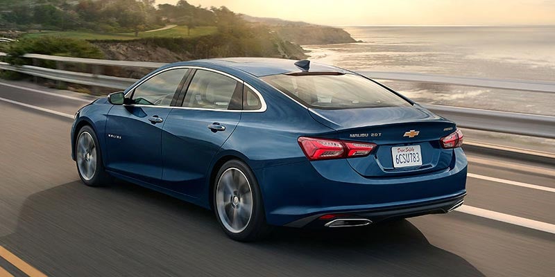 Blue Chevrolet Malibu cruising by the seaside.
