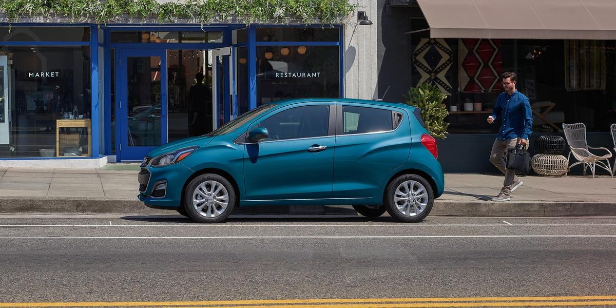 Chevrolet Spark parked on road and a man coming towards it.