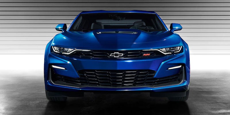 Bold front view of a blue Chevrolet Camaro illuminated by showroom lights