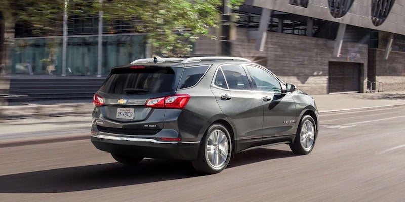 Rear view of a gray 2021 Chevrolet Equinox driving through a city street.