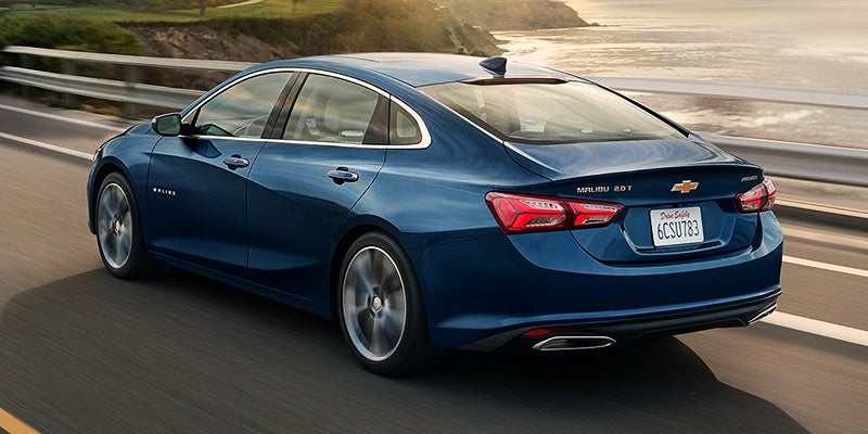 Blue Chevrolet Malibu cruising by the seaside.