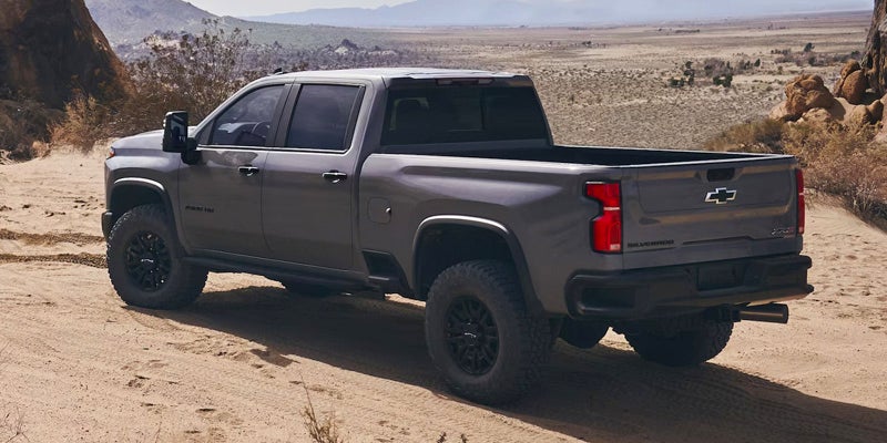 Rear view of a black Chevrolet Silverado 2500 HD ZR2 pickup truck driving through the desert