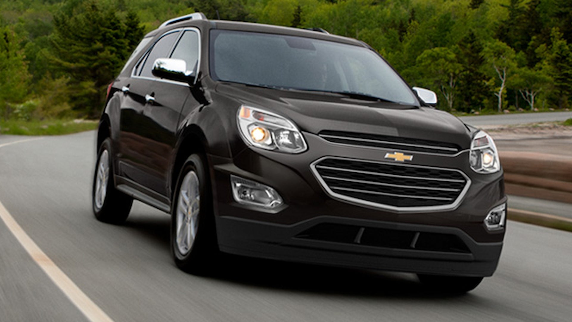 Front view of a 2017 Chevrolet Equinox driving on a winding road surrounded by green trees