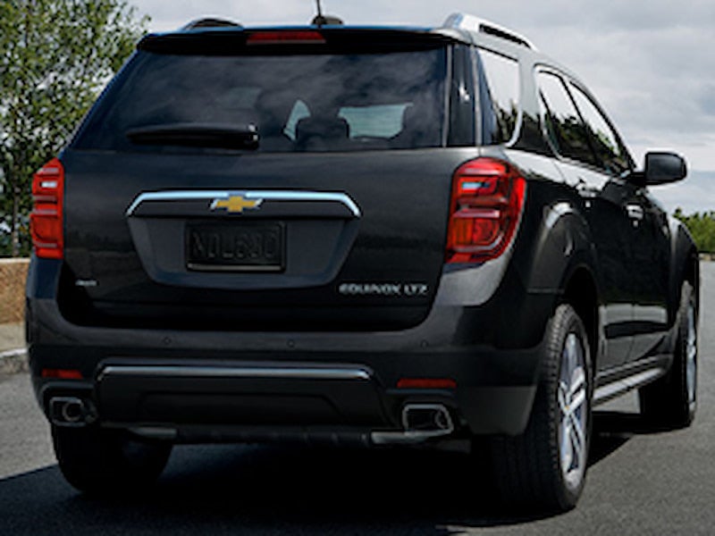 Rear view of a black 2016 Chevrolet Equinox LTZ parked on a road under cloudy skies.