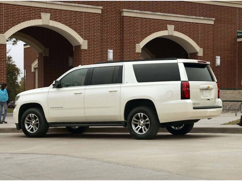 2017 Chevrolet Suburban in white parked in front of a red brick school building